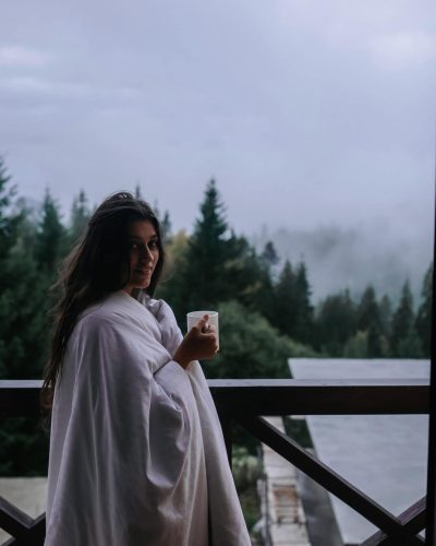 Young woman drinking tea on cozy balcony of a country house.